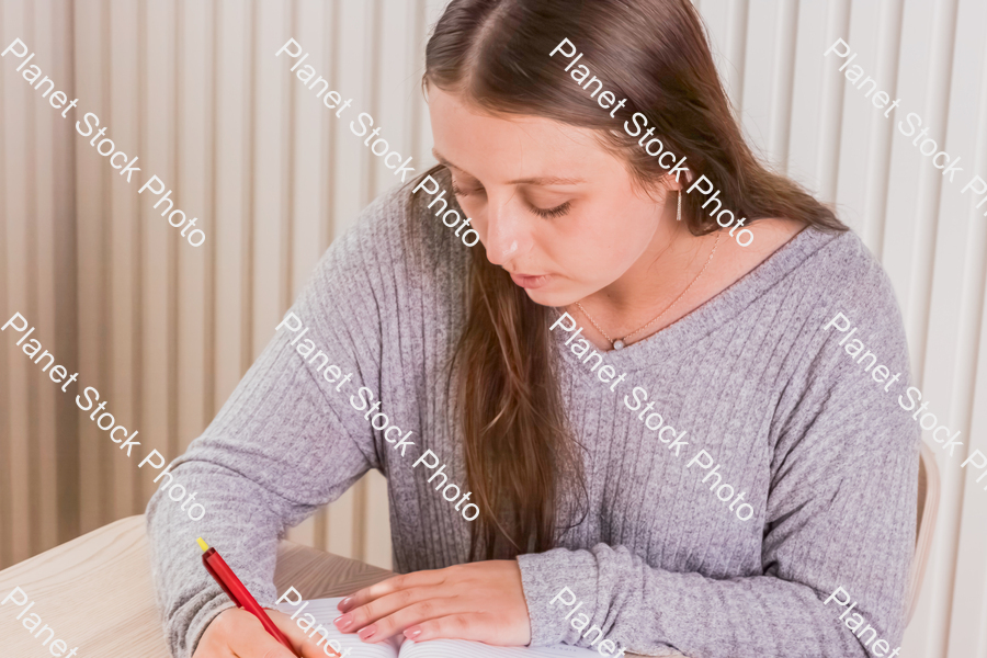 A girl writing in a journal stock photo with image ID: 047736e1-8d1e-4279-b1dc-9823583b5908