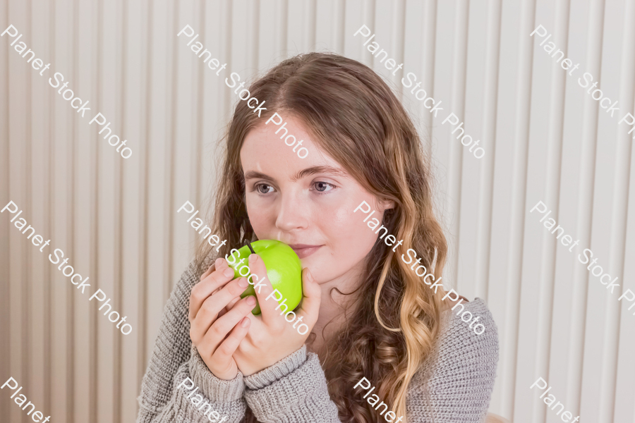 A girl sitting with an apple in her hand stock photo with image ID: 15c152c2-36fe-4912-8ba3-475bd5369e46