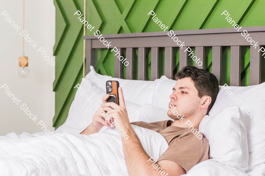 A young man in bed using a mobile phone stock photo with image ID: 15f5ee71-0fef-4396-a67d-0defa26446cc