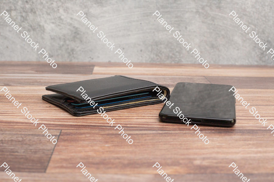 A mobile phone, with a black leather wallet stock photo with image ID: 220a463e-0d85-4f75-84a0-2dc5edba92b6