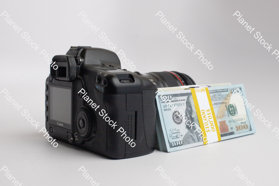 Three stacks of dollar bills, with a digital DSLR camera stock photo with image ID: 22a330ef-fac9-49df-9f7f-dd44e0b59cc4