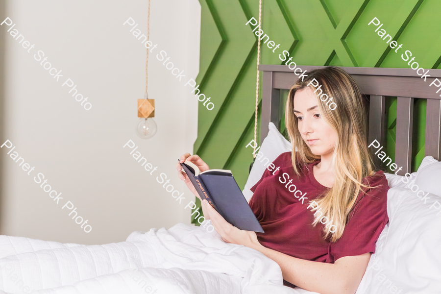 A young woman reading in bed stock photo with image ID: 28ac632d-5cfc-482f-a4c9-928f5ec2de0b