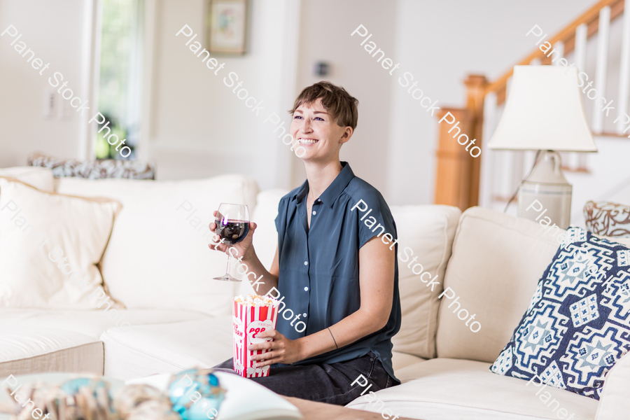 A young lady sitting on the couch watching a movie stock photo with image ID: 37f7de51-b64e-4e81-a85e-05bd8354beb6