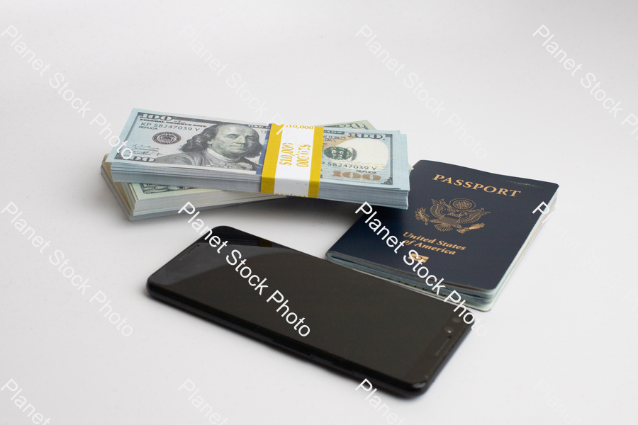 Three stacks of dollar bills, with  a US passport, and mobile phone stock photo with image ID: 40228f50-8542-45bb-8360-43e7f7a86538