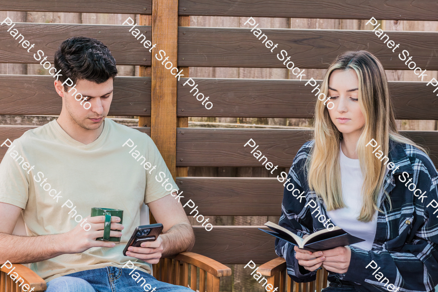 A young couple sitting outdoors stock photo with image ID: 43bc6e71-b57f-400c-8ba1-b5a2c5527b0d