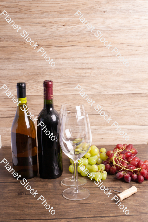 Two bottles of wine, with corkscrew, grapes, and wine glasses stock photo with image ID: 51747a62-267d-4360-8a1c-ea657be647a9