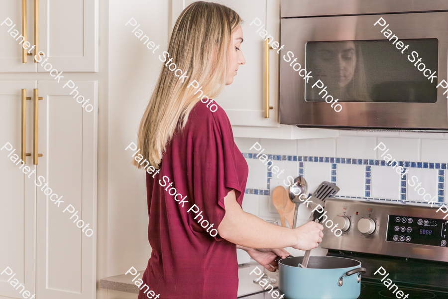 A young woman preparing a meal in the kitchen stock photo with image ID: 547d429e-469d-42e3-a1f0-c7470d7c05df