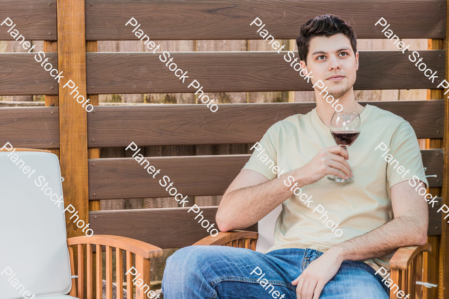 A young man sitting outdoors enjoying red wine stock photo with image ID: 5b87a743-4a1c-41d1-8702-3804bbebe90c