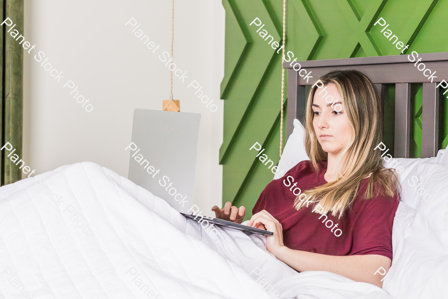 A young woman using a laptop in bed stock photo with image ID: 5bd62f14-17f6-4855-97ec-fd90c8a8611d