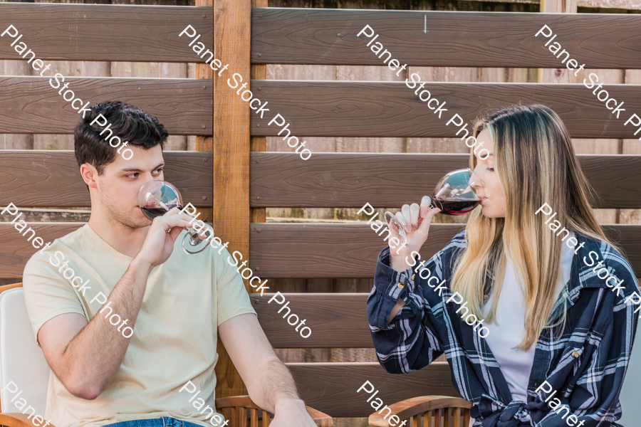 A young couple sitting outdoors, enjoying red wine stock photo with image ID: 60de6a67-1575-4a63-a408-ff51a543bc99