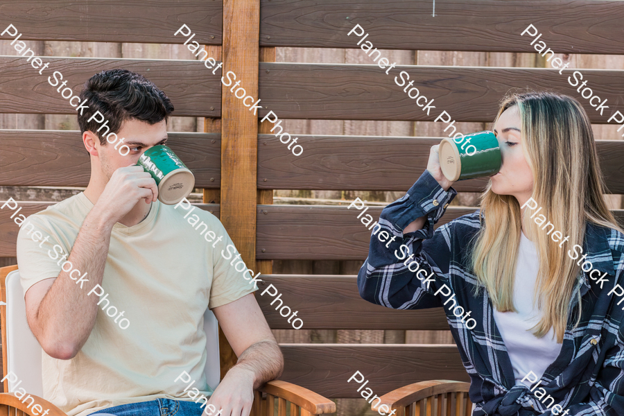A young couple sitting outdoors, enjoying hot drinks stock photo with image ID: 6ec54902-5436-4081-bad7-4f132adcf3f5