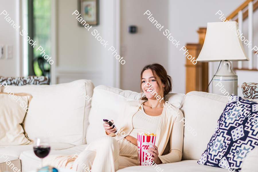 A young lady sitting on the couch watching a movie stock photo with image ID: 79cafe96-1907-4842-ad9b-a0e6174663e9