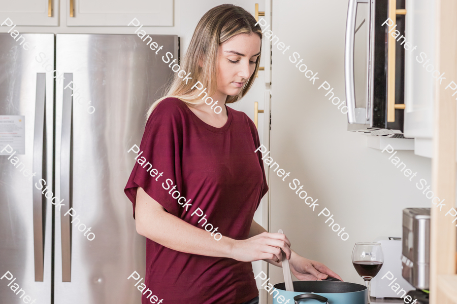 A young woman preparing a meal in the kitchen stock photo with image ID: 8acbef17-9678-4f6f-81a4-2d4b2de92459
