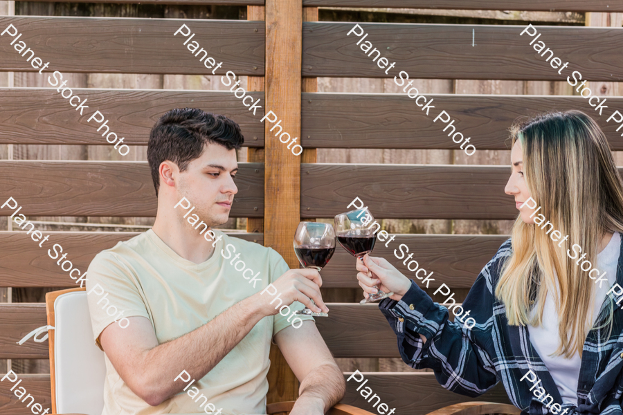 A young couple sitting outdoors, enjoying red wine stock photo with image ID: 941c99e7-1af5-4040-8717-39754abe870c