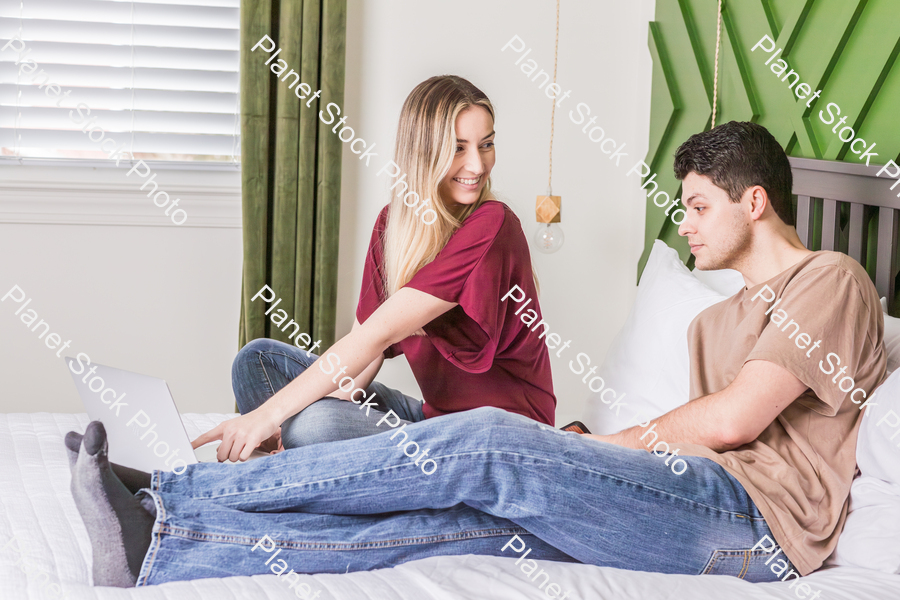 A young couple sitting in bed stock photo with image ID: 9e0dbd26-bd7f-4002-893c-f4d7a01b2355