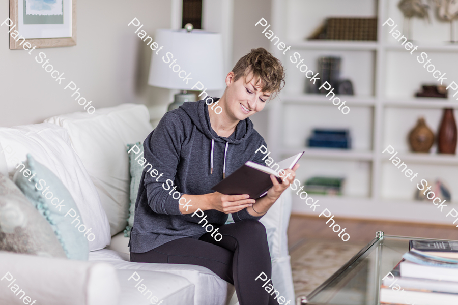 A young lady sitting on the couch stock photo with image ID: a13b593d-4315-4750-b48c-79db4f87a8cd