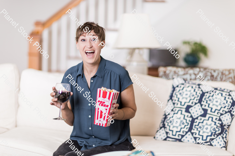 A young lady sitting on the couch watching a movie stock photo with image ID: a72c9da3-fa96-40eb-a28b-0397ec5652ef