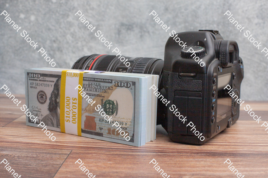 Three stacks of dollar bills, with a digital DSLR camera stock photo with image ID: a8ade195-1594-42d7-96b4-770e29a5a82a