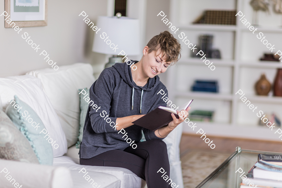 A young lady sitting on the couch stock photo with image ID: ac509a6b-e26b-4e4d-8294-6cc175a91838