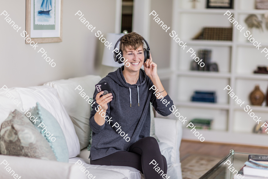 A young lady sitting on the couch stock photo with image ID: b18e3973-04e3-4d7e-a827-6c4b230acba0