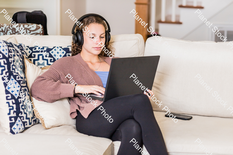 A young lady sitting on the couch stock photo with image ID: c9e7810c-c3fc-4abf-91cf-80e03b9fda32