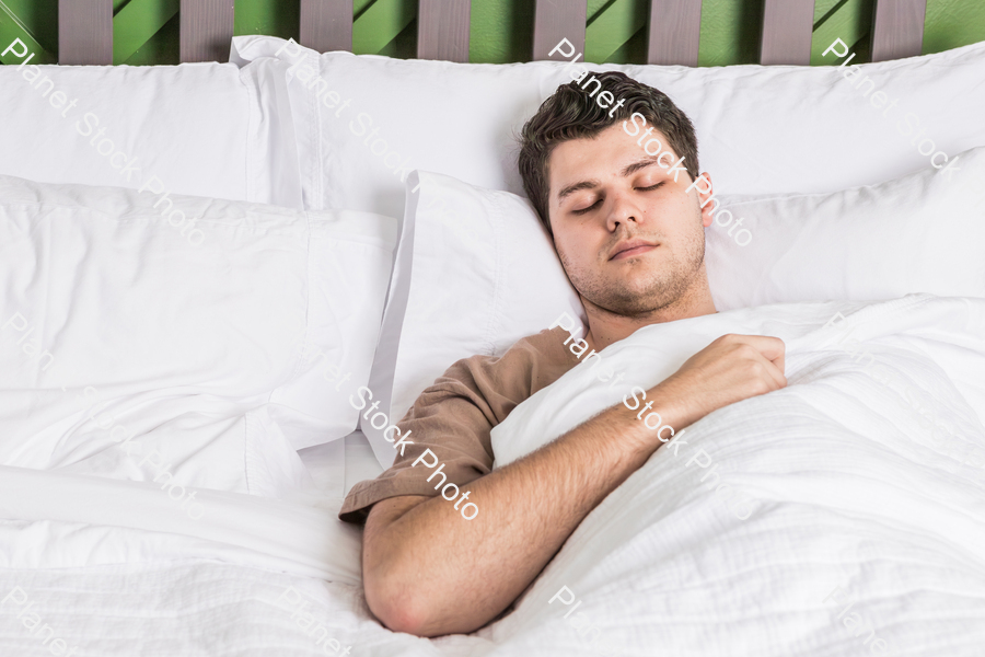 A young man sleeping in bed stock photo with image ID: cb8e8c23-d7f0-4334-88ee-b81f2aad665e