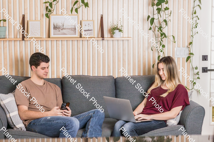 A young couple sitting on the couch stock photo with image ID: cb9c9dee-dc18-478e-90f4-ed522b347ca4