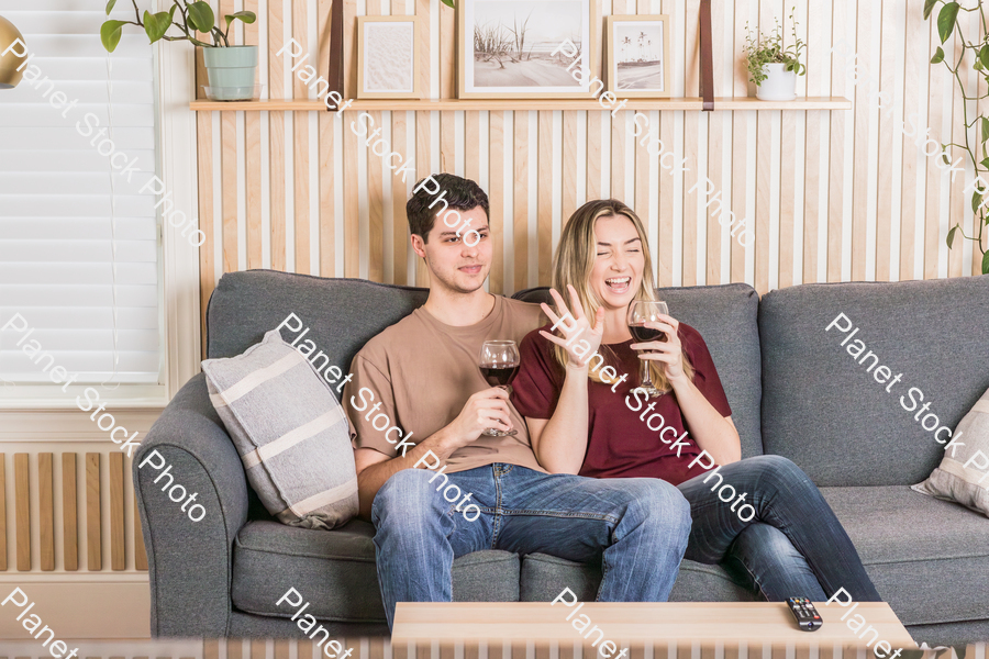 A young couple sitting on the couch and enjoying red wine stock photo with image ID: d4176b69-f9fb-4cfa-90b4-f110d9cf80a2