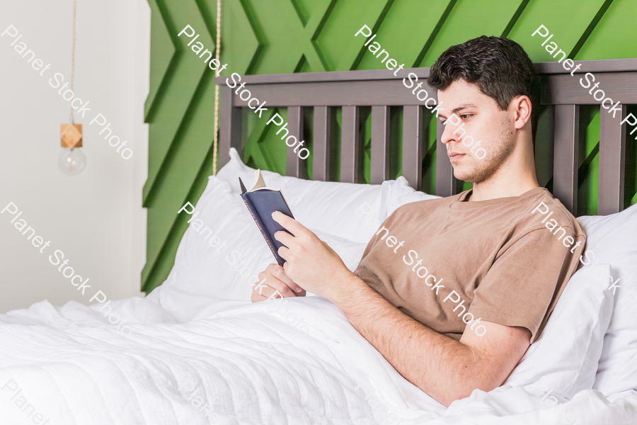 A young man reading in bed stock photo with image ID: d6fc7602-07b2-4ea6-8830-02607da9705f