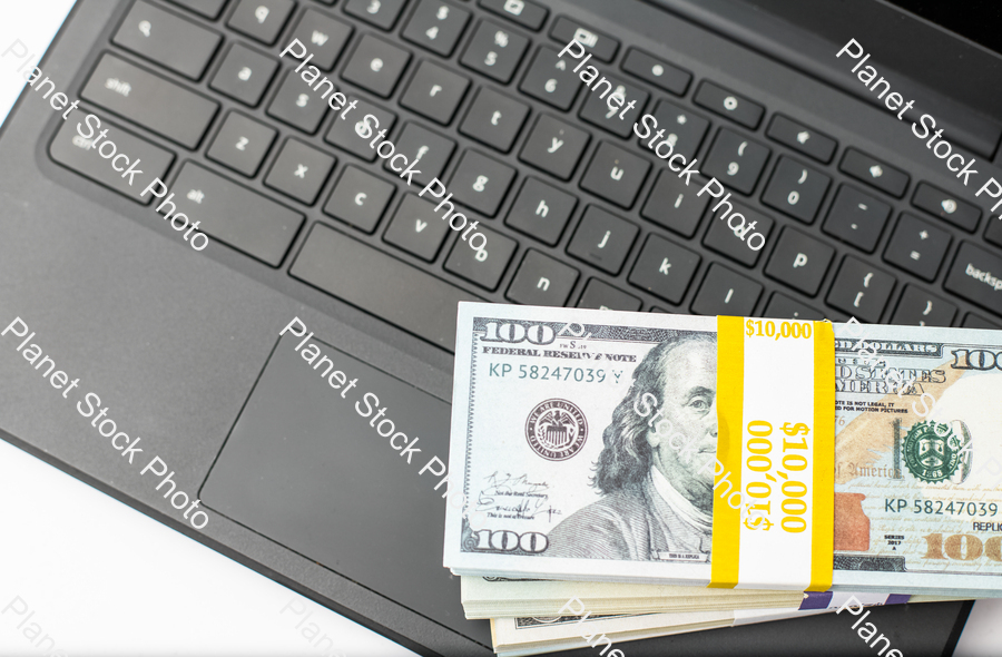 Three stacks of dollar bills on a laptop computer stock photo with image ID: d77bf3f6-ac8c-400f-bd0b-1d29a75b6c85