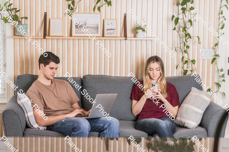 A young couple sitting on the couch stock photo with image ID: d9781ed3-078a-425f-9174-03874b6dc240