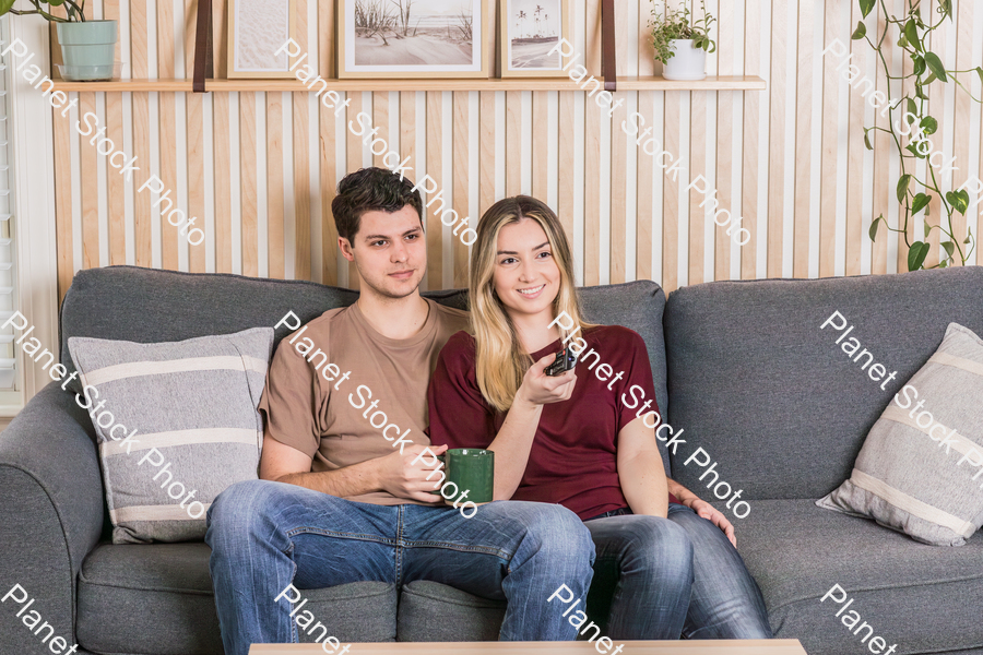 A young couple sitting on the couch watching a movie stock photo with image ID: d98c5195-3f6d-468d-be82-018ffd9f79fb
