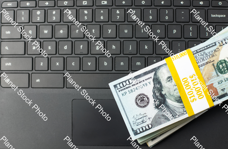 Three stacks of dollar bills on a laptop computer stock photo with image ID: dfbaf315-d630-4225-82f4-1a525296e2a8