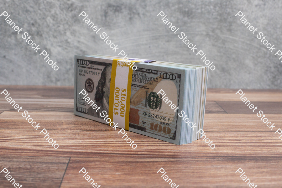 Three stacks of dollar bills, on a wood surface stock photo with image ID: e0ceeed9-2556-497e-ad52-10699e02a401