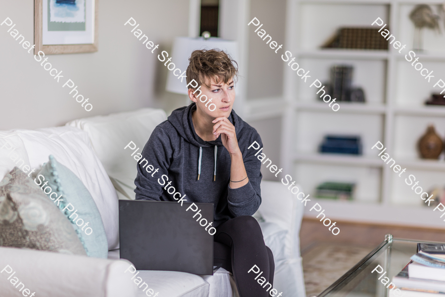 A young lady sitting on the couch stock photo with image ID: e4f38c89-cc0f-4490-ba6c-2fe6f4a750a0