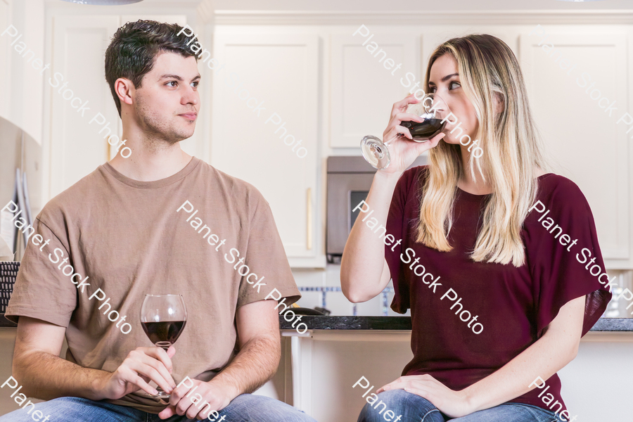 A young couple sitting and enjoying red wine stock photo with image ID: ee0ccc19-16c2-480d-b291-118fbc7e3228
