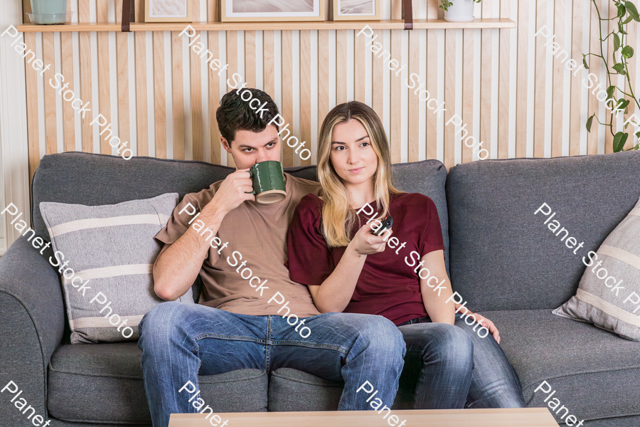 A young couple sitting on the couch watching a movie stock photo with image ID: f1bf9349-b36d-4e43-8a4a-4fd8bf7d4303