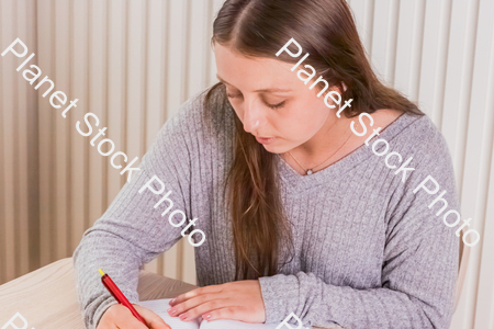 A girl writing in a journal stock photo with image ID: 047736e1-8d1e-4279-b1dc-9823583b5908