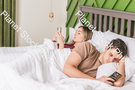 A young couple lying in bed stock photo with image ID: 04e80db8-e774-43d9-8bb8-e75da16356d8