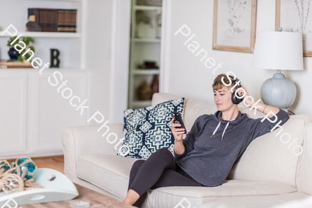 A young lady sitting on the couch stock photo with image ID: 14770de0-0a13-46eb-819e-a10dac3ec615