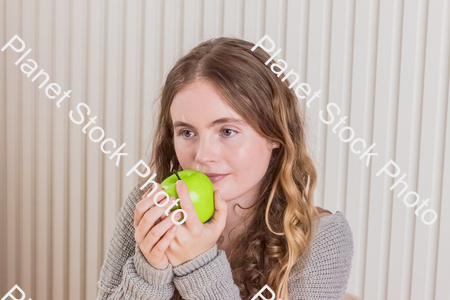 A girl sitting with an apple in her hand stock photo with image ID: 15c152c2-36fe-4912-8ba3-475bd5369e46