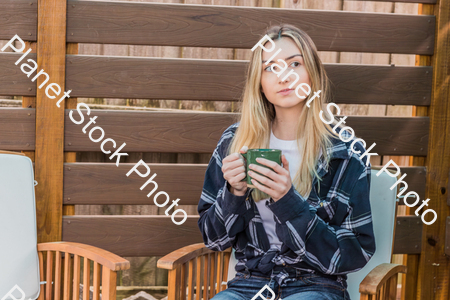 A young woman sitting outdoors enjoying a hot drink stock photo with image ID: 21aedcab-4a85-47ff-8fdc-b7d105c8940e