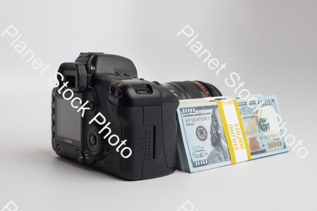 Three stacks of dollar bills, with a digital DSLR camera stock photo with image ID: 22a330ef-fac9-49df-9f7f-dd44e0b59cc4