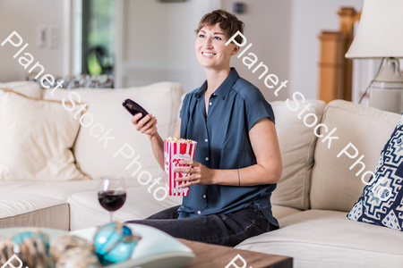 A young lady sitting on the couch watching a movie stock photo with image ID: 569fb924-fc1a-4e89-a5ef-81db42a84a18