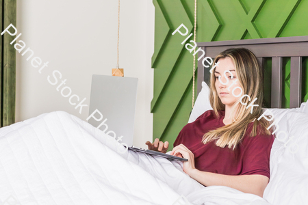 A young woman using a laptop in bed stock photo with image ID: 5bd62f14-17f6-4855-97ec-fd90c8a8611d
