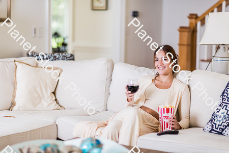 A young lady sitting on the couch watching a movie stock photo with image ID: 63b37cff-4c96-4dcb-ba82-181a6bbba8f0