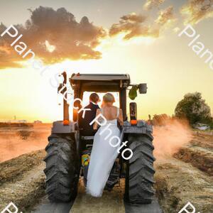 A Newly Married Couple Driving a Tractor Through the Grain Field Towards the Horizon at Sunset stock photo with image ID: 67ccfbfa-a37e-41a8-b079-7c364b9a41be