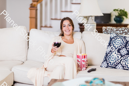 A young lady sitting on the couch watching a movie stock photo with image ID: 6b5d1e50-efd7-4728-af9d-f616813ad28b