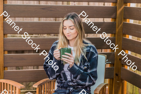 A young woman sitting outdoors enjoying a hot drink stock photo with image ID: 82727178-efe7-40cd-bb02-15890c92ba68