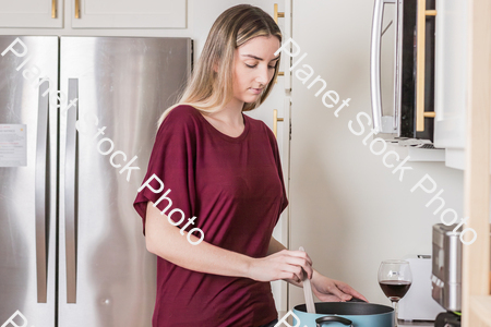 A young woman preparing a meal in the kitchen stock photo with image ID: 8acbef17-9678-4f6f-81a4-2d4b2de92459